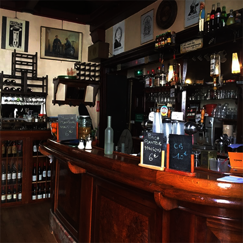 Photo intérieur de notre bar le Bab-Ilo concert jazz bar stand-up, situé au 9 rue du Baigneur Paris 75018, , ou l'on peut voir le comptoir en bois, un aperçu des boissons proposées et quelques tableaux, affiches, représentations au mur